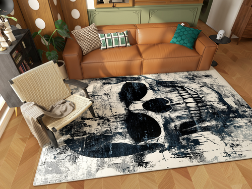 Load image 1 in gallery view. A modern living room with a brown leather sofa, patterned pillows, a woven chair, and the Faded Skull - Washable Rug - HLW008 (Custom Size), featuring a bold abstract black skull design on a light background.