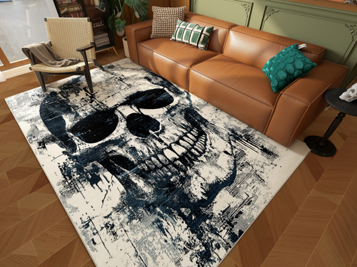 Load image 1 in gallery view. A modern living room with a tan leather sofa, patterned pillows, a wicker chair, and the Faded Skull - Washable Rug - HLW008 (Custom Size), featuring a bold abstract black and white skull design on parquet flooring.