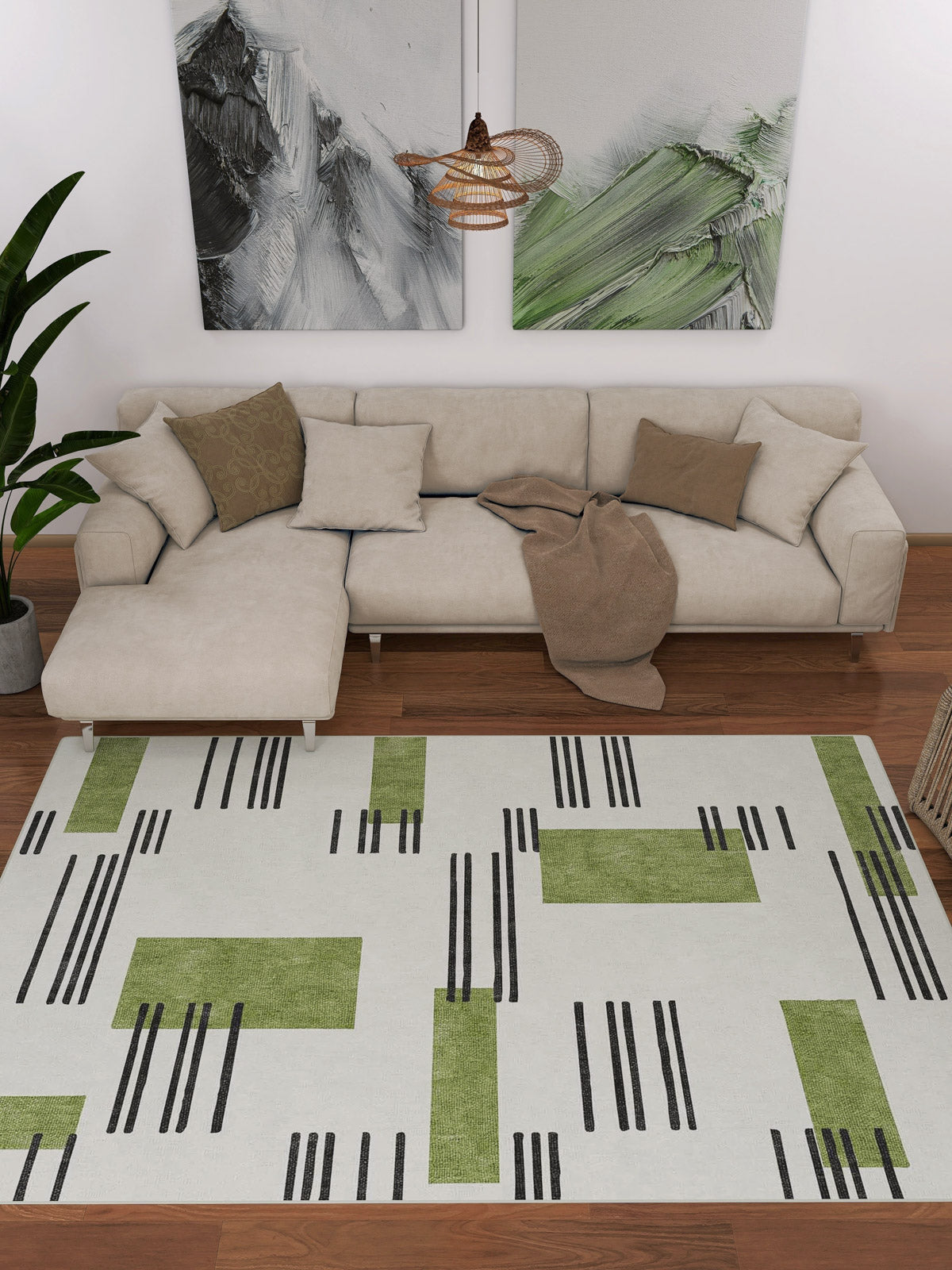 Modern living room with a beige sectional, green and brown pillows, a taupe throw, abstract wall art, a potted plant, and the Faded Treasure - Washable Rug - JRN46 featuring green blocks and black lines on a white background.