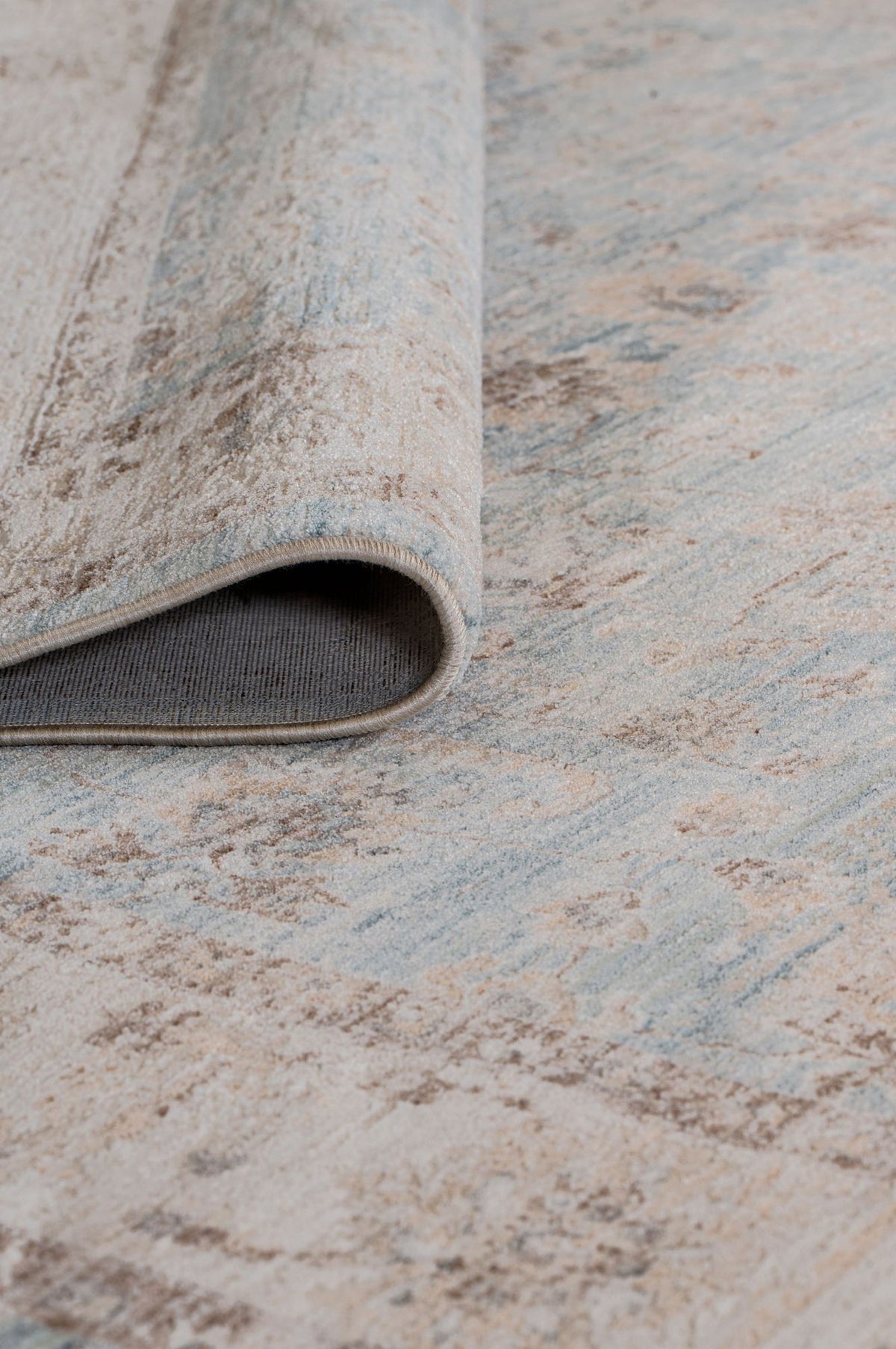 A close-up of the Faded Azure - Area Rug - APX2941 shows its blue and beige Persian-inspired abstract pattern with a textured underside, making it a stylish choice for any living room.