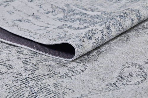Bild 1 in Galerieansicht laden. A close-up of the Faint Memories - Washable Rug - JR1437 (Custom Size), folded to display its light gray flat weave, subtle distressed dark gray pattern on a light background, highlighting texture and weave detail.