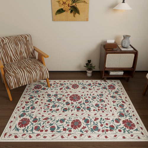 Load image 1 in gallery view. A cozy room with a zebra-print armchair, the Floral Ivory - Washable Rug - JRN1025 (Custom Size) featuring red, green, and blue florals—ideal for high-traffic areas—a small plant, a wooden cabinet with books and vase, and a wall lamp under botanical art.