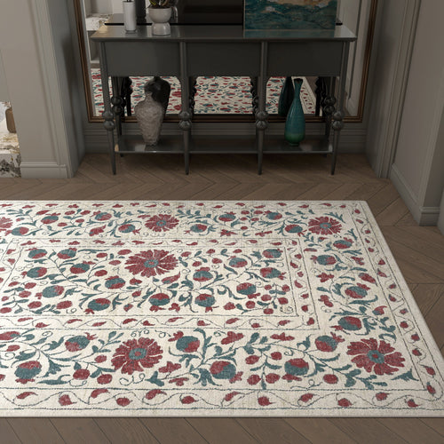 Load image 1 in gallery view. The Floral Ivory - Washable Rug - JRN1025 (Custom Size) features red and blue floral patterns on a cream background, ideal for allergy-sensitive homes or high-traffic areas, and looks stylish in front of a gray console table beneath a mirror.