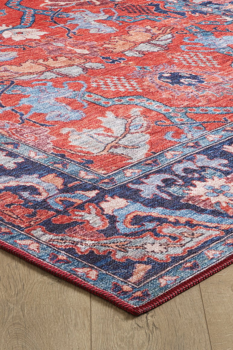 A close-up of the Galea Turkish-Design Coral Washable Rug (LCC3027) shows its vibrant red, blue, and purple floral patterns and detailed border on a wooden floor—ideal for high-traffic areas due to its washable design.