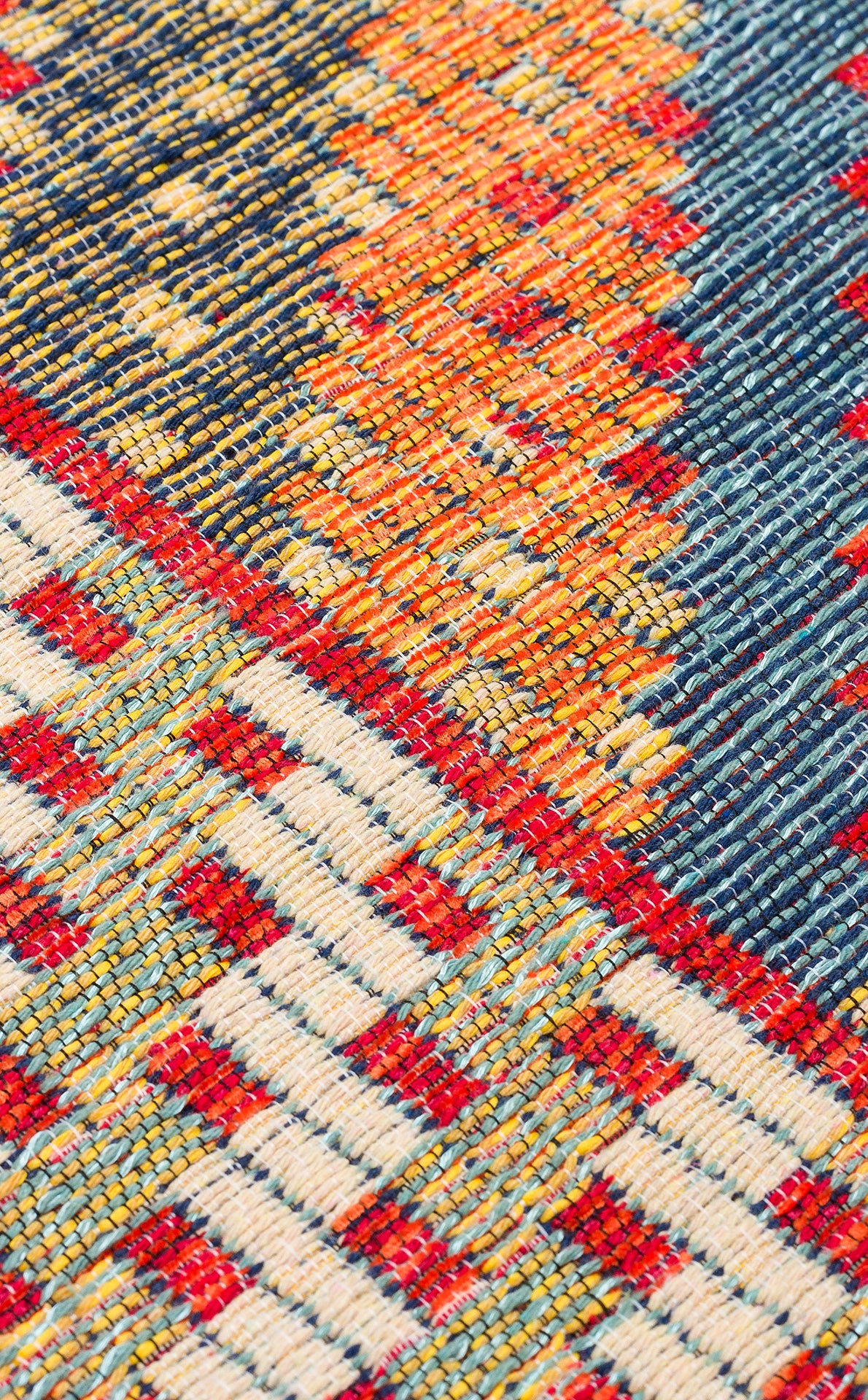 Close-up of the Garnet Print - Washable Reversible Kilim (NMD10), a flatwoven rug with geometric patterns in red, yellow, orange, blue, and white, highlighting its textured surface and visible threads.