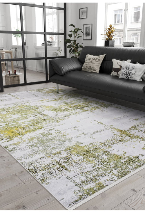 Load image 1 in gallery view. A modern living room features a black sofa, decorative pillows, plants, and large windows. The Geometric Geometry - Washable Rug - JR1290 in green adds a pop of color, while neutral tones and minimal decor create a cozy, stylish vibe.