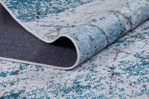 Load image 1 in gallery view. A close-up of the Geometric Glimmers - Washable Rug - JR1423 (Custom Size) in blue and gray, partially folded to show its marbled pattern, durable edging, and easy-care underside—ideal for high-traffic spaces.