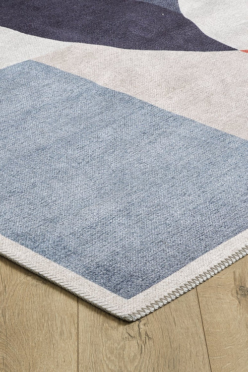 Load image 1 in gallery view. A close-up of the Geometric Zen Modern Washable Rug - MDJ002, allergy-sensitive and featuring a blue, purple, and beige geometric pattern with a zigzag-stitched edge for style and durability, shown on a light wooden floor.