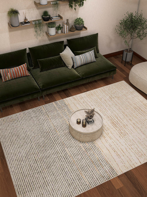 Load image 1 in gallery view. Modern living room featuring the Gilded Charm - Washable Rug - JRN26, a green velvet sofa with assorted cushions, round marble coffee table with decor, wall-mounted shelves with plants, and wooden floors.