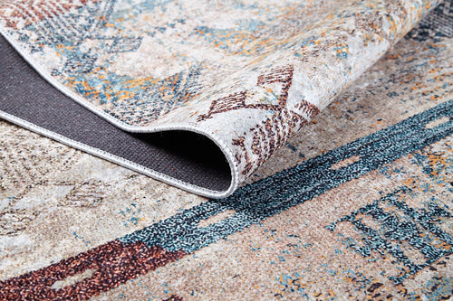 Load image 1 in gallery view. A close-up of the Global Glamour - Washable Rug - JR1708 (Custom Size) with a folded corner shows its textured backing. The rug’s abstract geometric design in earthy tones with blue, brown, and beige suits high-traffic areas.
