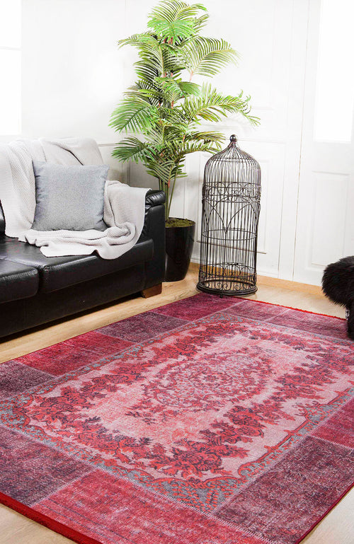 Load image 1 in gallery view. A cozy living room with a black couch, gray blanket and pillow, the Golden Wonder - Washable Rug - JR306 (Custom Size) in red—ideal for high-traffic areas—a tall potted plant, decorative birdcage, and white walls with natural light.