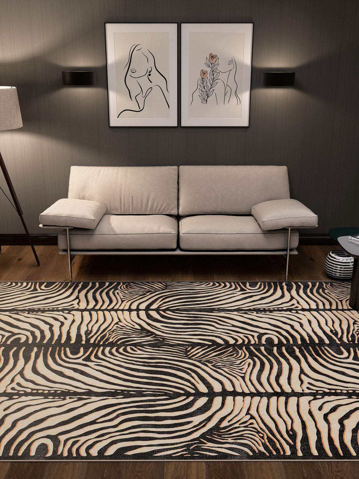 A modern living room with a beige sofa, two minimalist line art prints above it, wall sconces, a floor lamp, and the Gossamer Fade - Washable Rug - JRN44 in custom size featuring black and white swirl patterns.