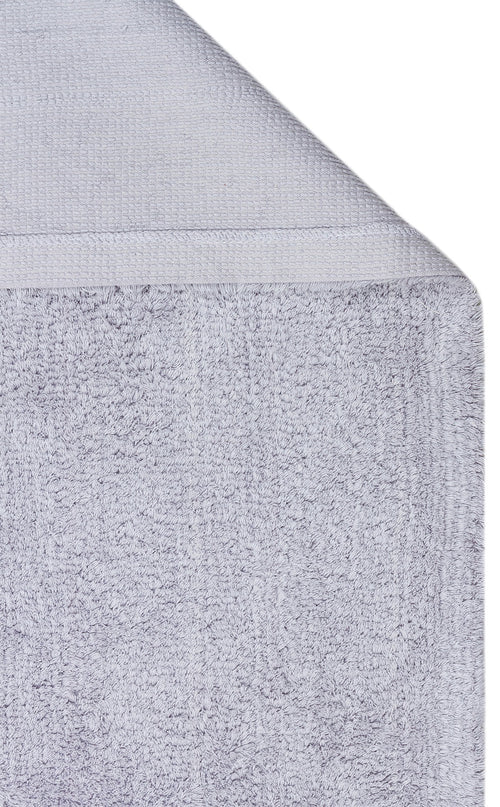 Load image 1 in gallery view. A close-up of the Grey Snug - Washable Shaggy - CBNPLAIN, neatly folded to display its soft, textured fabric and woven border—perfect for adding a cozy, coordinated touch to any modern bedroom or grey cotton rug ensemble.