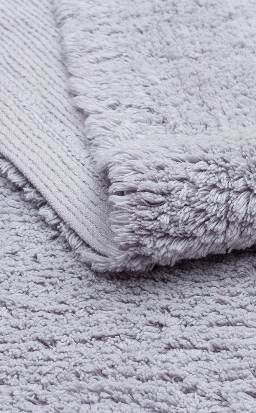 Load image 1 in gallery view. A close-up of the Grey Snug - Washable Shaggy (CBNPLAIN) rug shows its soft, textured light gray, fluffy pile with a slightly raised surface and a visible woven underside corner.