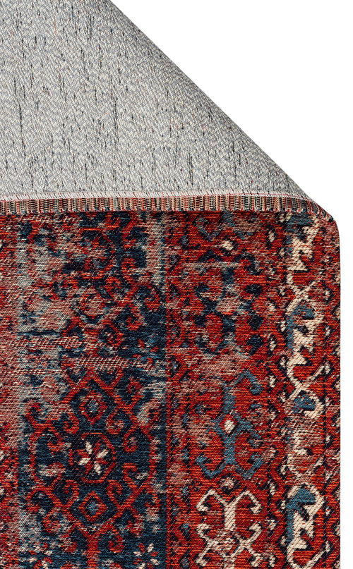 Load image 1 in gallery view. A close-up of the Heritage Blend - Washable Kilims - AND02 rug shows its red and navy chenille polyester pattern and decorative border. The corner is flipped to display a gray, dotted non-slip backing—an allergy-conscious choice.