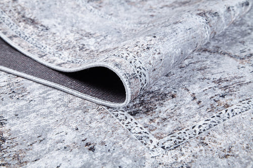 Load image 1 in gallery view. A close-up of the Heritage Jewel - Washable Rug - JR1778 (Custom Size) in gray-anthracite shows its abstract, textured pattern. A folded corner reveals the darker, non-slip backing—ideal for high-traffic spaces.