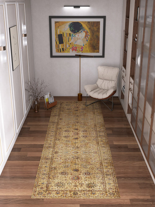 Load image 1 in gallery view. A hallway with wooden floors showcases the Heritage Threads - Washable Rug - JRN1007 runner, paired with a cushioned chair, wooden floor lamp, tall vase with branches, shelf of books, and framed abstract wall art for timeless traditional style.
