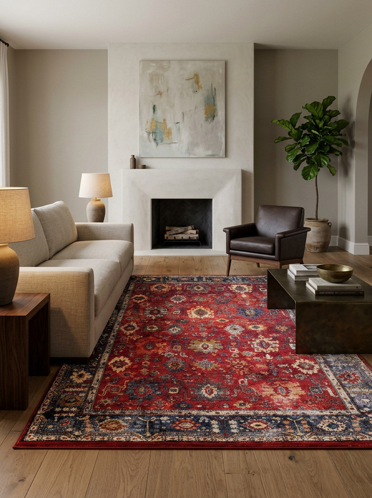 A modern living room features a beige sofa, brown armchair, and wooden coffee table atop the Historic Hues - Washable Rug - JR898, perfect for high-traffic areas. A fireplace with abstract art, a potted plant, and ample natural light complete the space.
