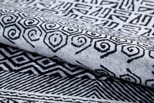 Load image 1 in gallery view. Close-up of Indie Impressions - Washable Rug - JR1648 (Custom Size) features folded flat weave fabric with intricate black geometric and spiral patterns on a light gray background, showing crisp lines and a soft, textured surface.