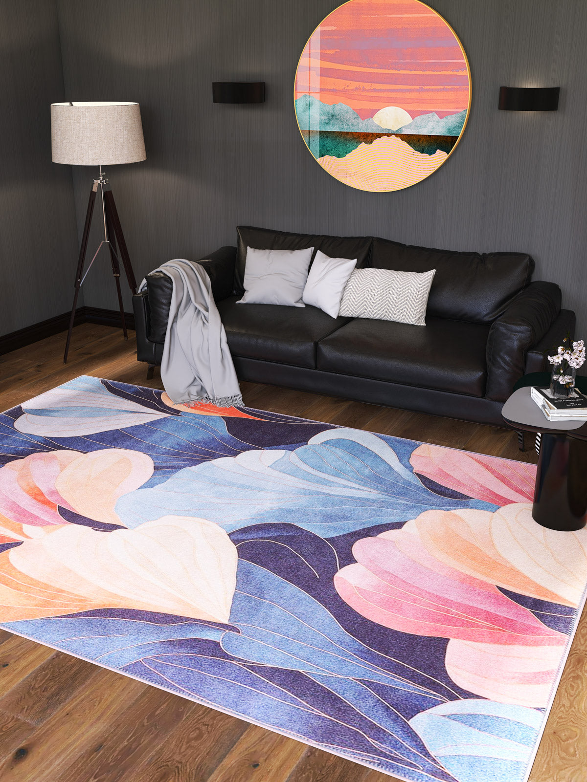 A modern living room with a black sofa, floor lamp, round colorful landscape wall art, and the Iris Abstract Floral Washable Rug - MDJ009 in blue, pink, peach, and purple abstract shapes on a wooden floor.