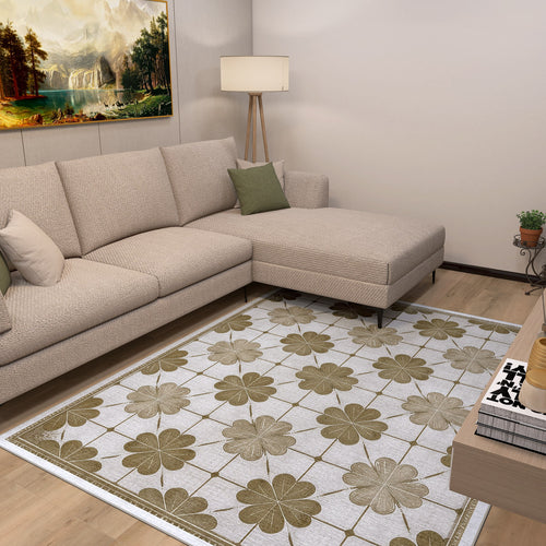 Load image 1 in gallery view. A modern living room features a beige sectional sofa with green pillows, a floor lamp, landscape painting, and the Ivory Clover - Washable Rug - JRS014 with a large green and brown floral design—perfect for high-traffic areas. A small plant sits in the corner.