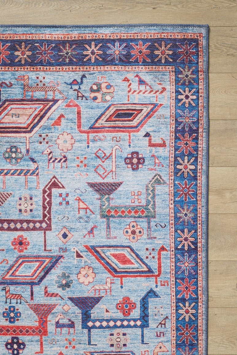 The Birdwatcher's Dream Blue Washable Rug - LCC3020 features geometric animal and floral patterns in red and cream, a star motif border, and is perfect for high-traffic areas on light wooden floors.