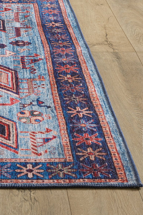 Load image 1 in gallery view. A close-up of the Birdwatcher's Dream Blue Washable Rug - LCC3020, featuring vibrant geometric and floral patterns in blue, red, and cream on a light wooden floor—perfect for high-traffic areas.