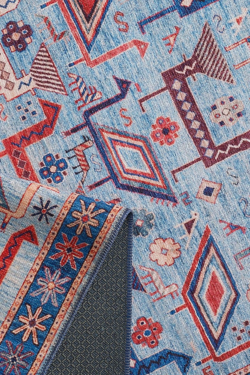 Load image 1 in gallery view. Close-up of the Birdwatcher's Dream Blue Washable Rug - LCC3020 (Custom Size) featuring colorful geometric and floral patterns in blue, red, and cream; a flipped corner reveals textured backing—perfect for high-traffic areas.
