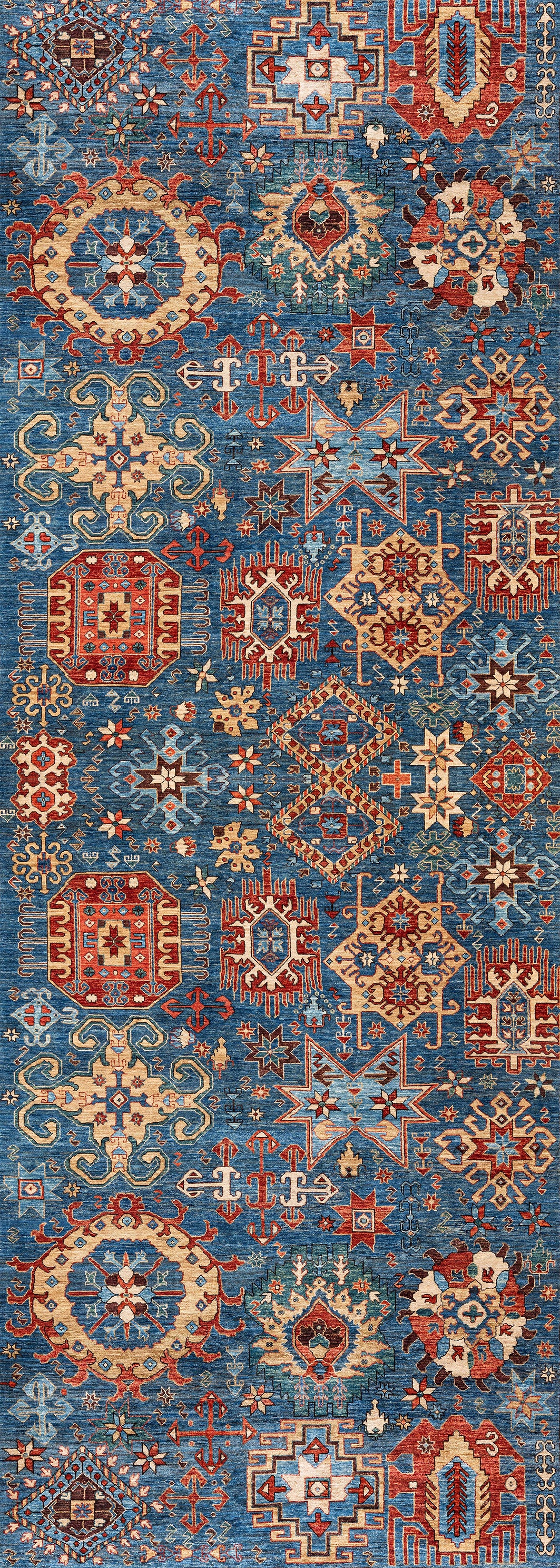 The Kaleidos Authentic Blue Washable Rug - LCC3028 features intricate geometric and floral patterns in red, gold, cream, and brown on a blue background. Its symmetrical design brings vibrant, traditional style—ideal for high-traffic areas and easy to clean.