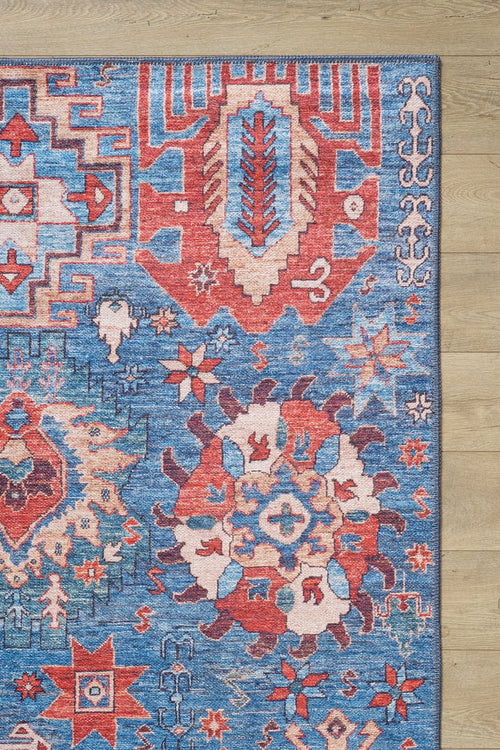 Load image 1 in gallery view. The Kaleidos Authentic Blue Washable Rug - LCC3028 features intricate geometric and floral patterns in red, blue, white, and beige. Only the top right corner of this colorful rug is visible on a light wood floor—ideal for high-traffic spaces.