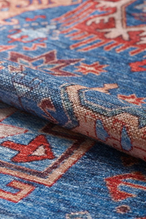 Load image 1 in gallery view. A close-up of the Kaleidos Authentic Blue Washable Rug - LCC3028 displays its blue, red, and beige geometric pattern and textured surface with a slight fold—perfect for high-traffic areas.
