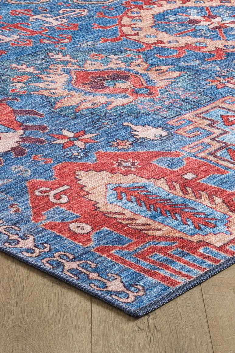 A close-up of the Kaleidos Authentic Blue Washable Rug - LCC3028, featuring bold geometric and abstract patterns in red, blue, and beige on a light wooden floor—ideal for high-traffic areas.