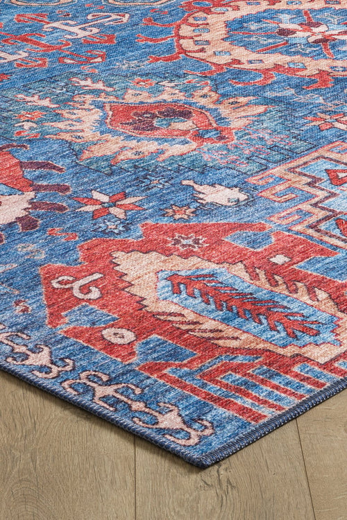 Load image 1 in gallery view. A close-up of the Kaleidos Authentic Blue Washable Rug - LCC3028, featuring bold geometric and abstract patterns in red, blue, and beige on a light wooden floor—ideal for high-traffic areas.
