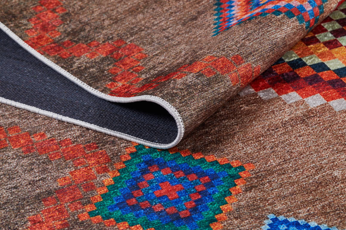 A close-up of the Kilim Kingdom - Washable Rug - JR1536 (Custom Size), featuring a brown woven texture and vibrant red, blue, and green geometric patterns; one corner is folded to show the dark underside—ideal for high-traffic areas.