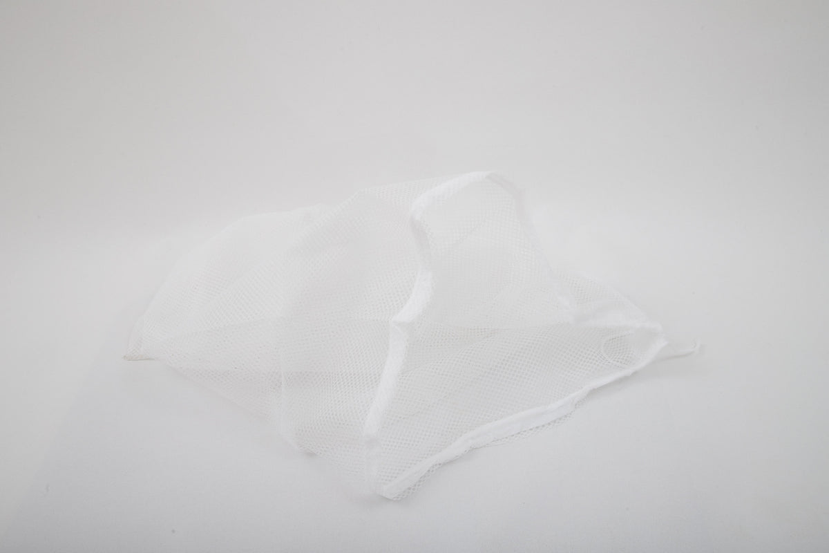 A Laundry Washing Bag made of white mesh fabric lies crumpled on a plain white background.