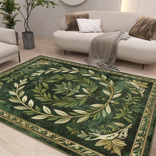 Load image 1 in gallery view. A modern living room with a white sofa, neutral cushions, and a gray throw features the Laurel Crown - Washable Rug - JRS024, showcasing an ornate olive leaf wreath and subtle geometric pattern. Plants and minimal decor complete the cozy, elegant space.