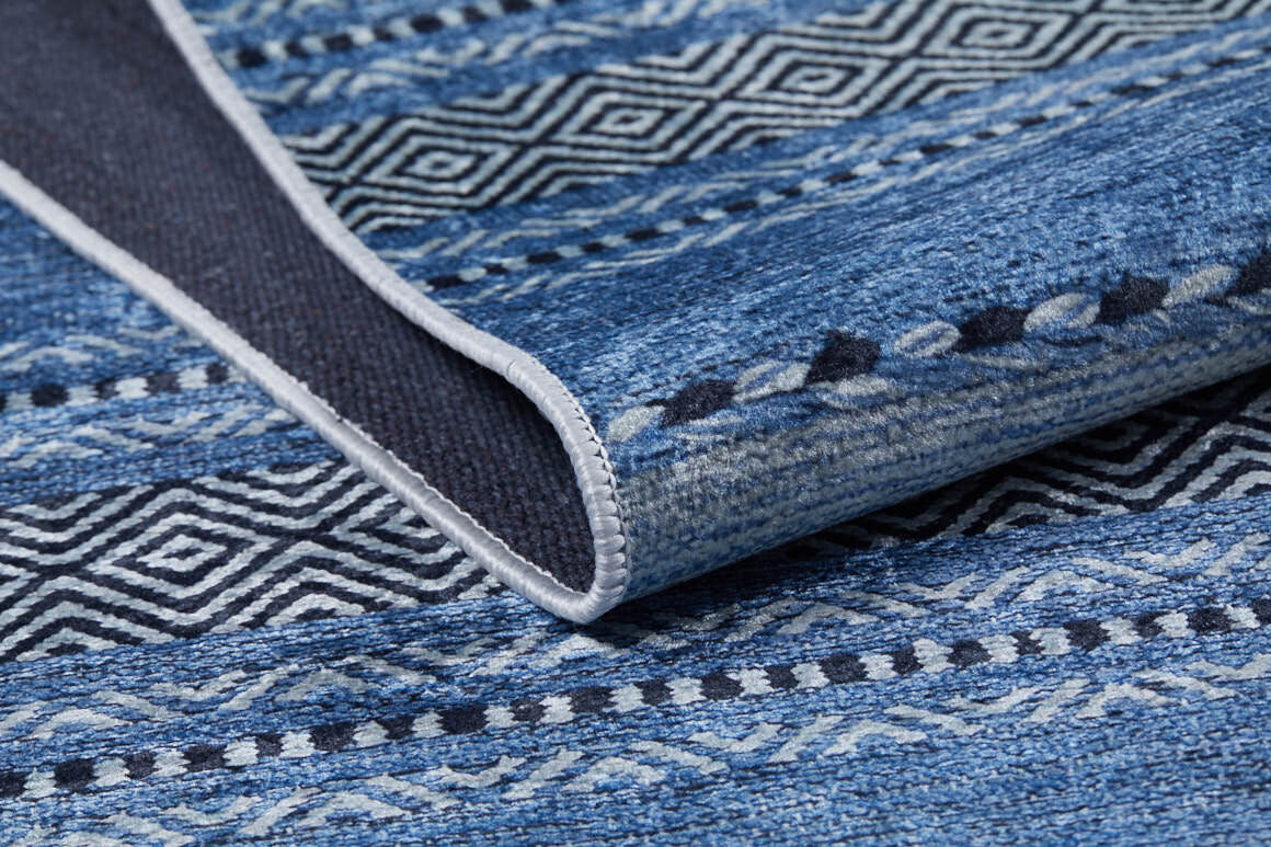 A close-up of the Layered Lines - Washable Rug - JR1545 (Custom Size) in blue, featuring geometric and tribal-inspired designs with folded edge showing underside and stitching—ideal for high-traffic areas.