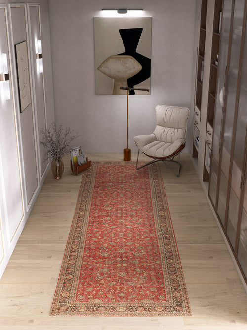 Load image 1 in gallery view. A Legacy Wreath - Washable Rug - JRN1024 with a red border runs down the center of a modern hallway with light wood floors, complemented by a lounge chair, floor lamp, abstract wall art, and shelves for a cozy reading nook.