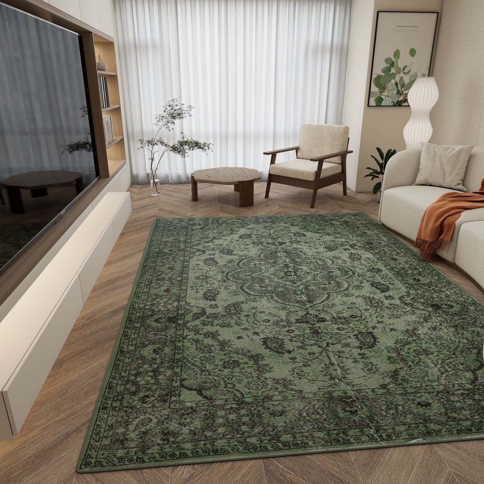 A modern living room with the Royal Vinework - Washable Rug - JRN1009 featuring a large green medallion design, paired with a beige sofa, orange throw, wood armchair, round ottoman, tall white lamp, plant, wall art, and TV facing tall sheer-curtained windows.