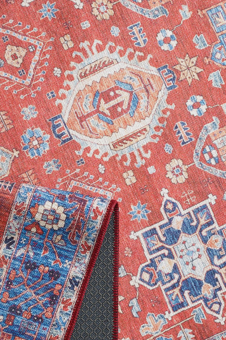 The Lunavale Red Blue Washable Rug - LCC3007 (Custom Size) features red, blue, cream, and gold geometric and floral patterns. Its flipped corner reveals a blue underside with matching motifs and textured backing—ideal for high-traffic areas.