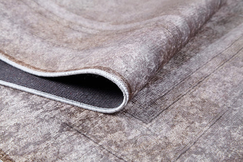 Load image 1 in gallery view. A close-up of the Luxe Borderline - Washable Rug - JR1741 (Custom Size) shows its curled corner, surface pattern, and stitched edges. In muted bronze and brown tones, it’s ideal for high-traffic areas and easy to clean.
