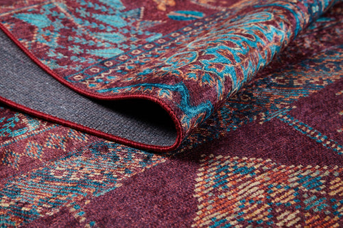 Load image 1 in gallery view. A close-up of the Majestic Mandarin - Washable Rug - JR1863 (Custom Size), showing its blue, red, and yellow patterns with a folded corner exposing the dark gray underside—an ideal stylish choice for high-traffic areas.
