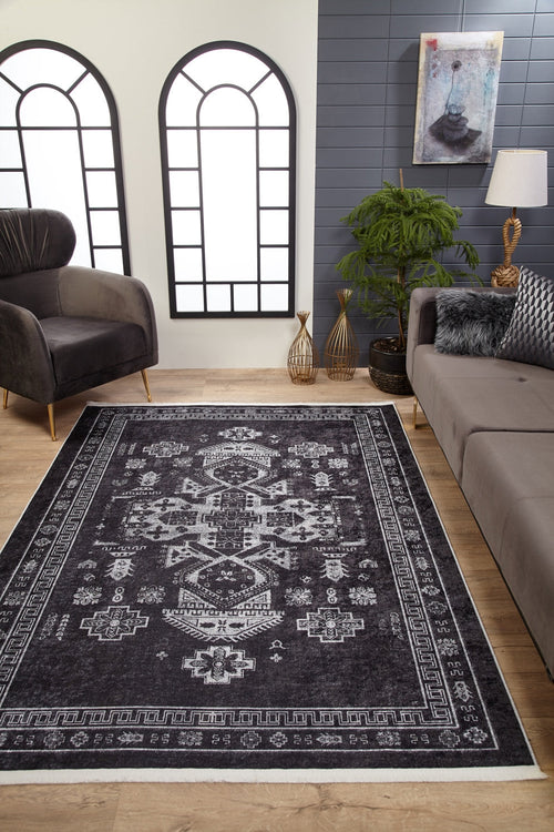 Bild 1 in Galerieansicht laden. A modern living room features wood flooring, a gray sofa, black armchair, indoor plants, decorative vases, large arched windows with white panes, and the Majestic Symbol - Washable Rug - JR1892 (Custom Size) on the floor beneath a painting.