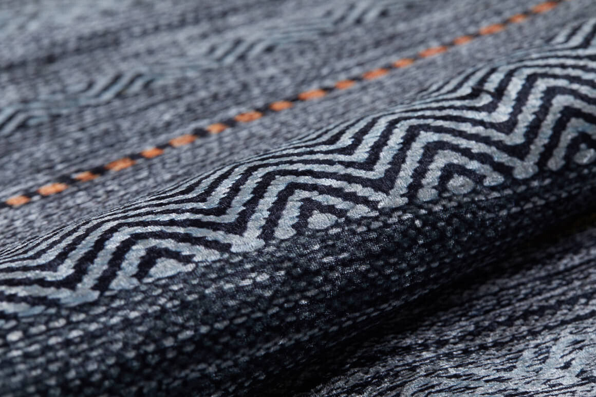 Close-up of the Metro Lines - Washable Rug - JR1548 (Custom Size) featuring a textured dark blue zigzag pattern and a single dashed orange line. The soft, intricately woven material is ideal for everyday use and easy to wash.