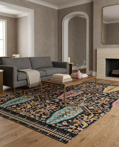 Bild 1 in Galerieansicht laden. A modern living room with a gray sofa, wooden coffee table, and the Midnight Bazaar Area Rug APX1911 on a wooden floor. A fireplace features a large mirror above it, and the neutral walls have white trim.