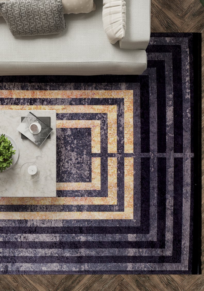 Modern living room with a white sofa, Minimalist and Clean - Washable Rug - JR1407 (Custom Size) in concentric purple and gold rectangles, marble coffee table with plant, candle, books—all on durable herringbone flooring.