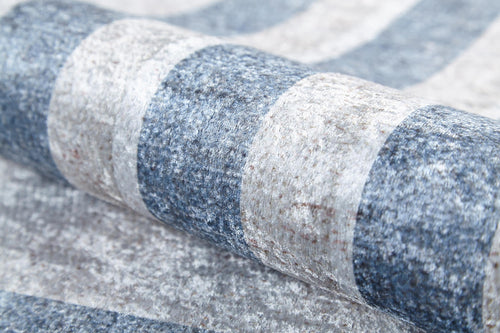 Load image 1 in gallery view. Close-up of the Modern and Regal - Washable Rug - JR1616 (Custom Size), featuring rolled-up textured blue and light gray stripes. This washable rug is perfect for high-traffic areas.