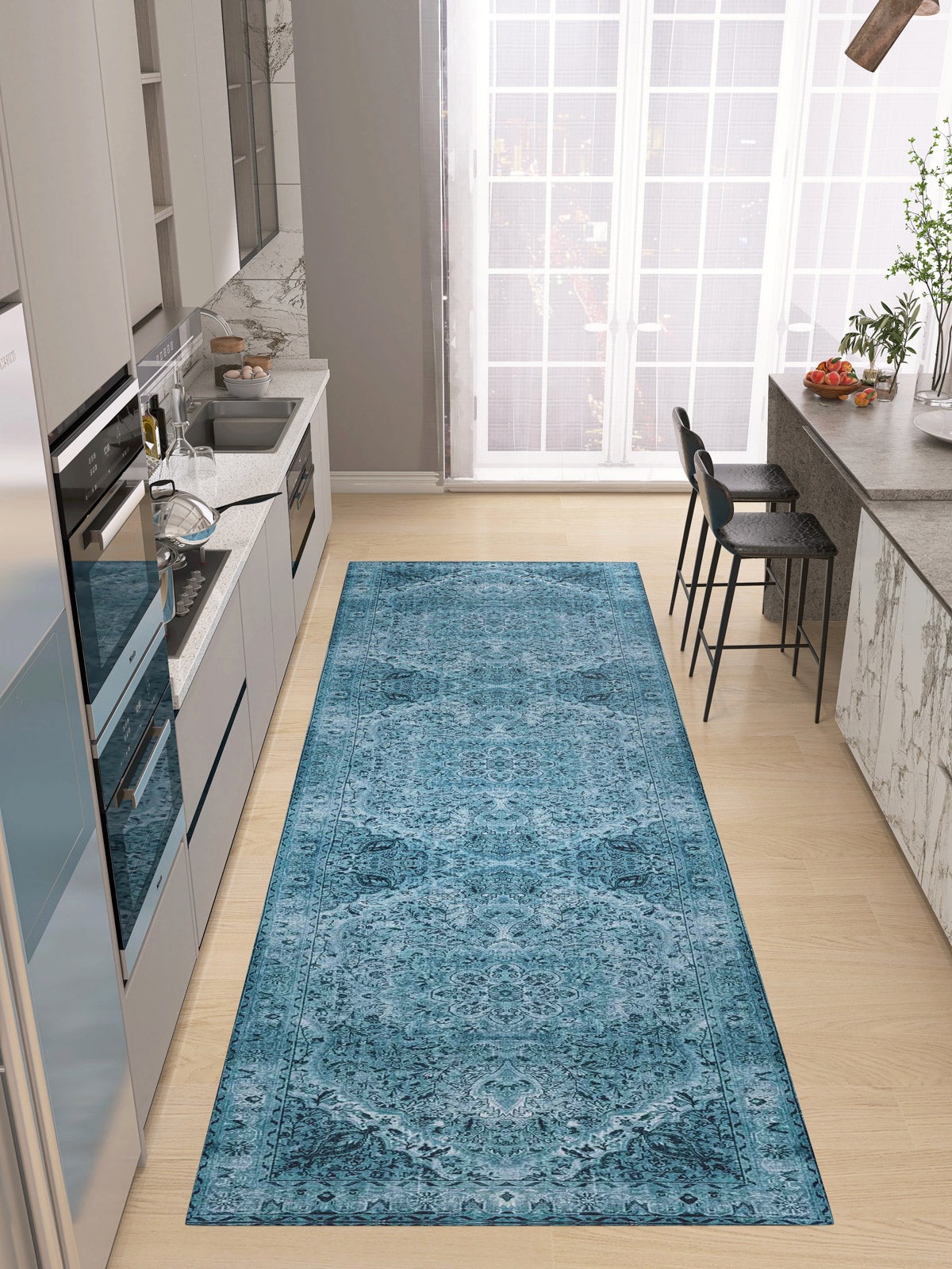 A modern kitchen with light wood floors, gray cabinets, and a Mystic Mosaic - Washable Rug - JRN1019 (Custom Size) leading to a breakfast bar with two black chairs by large floor-to-ceiling windows.