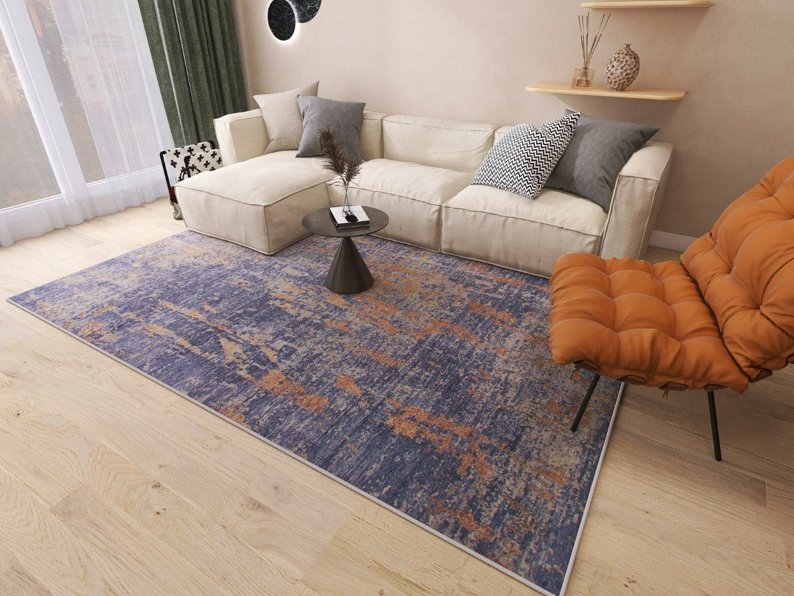 A modern living room features a beige sectional sofa, patterned pillows, a round black coffee table, an orange lounge chair, and the Mystical Mosaic - Washable Rug - JRS003 (Outlet) US—perfect for high-traffic areas. Light fills the space through large windows.