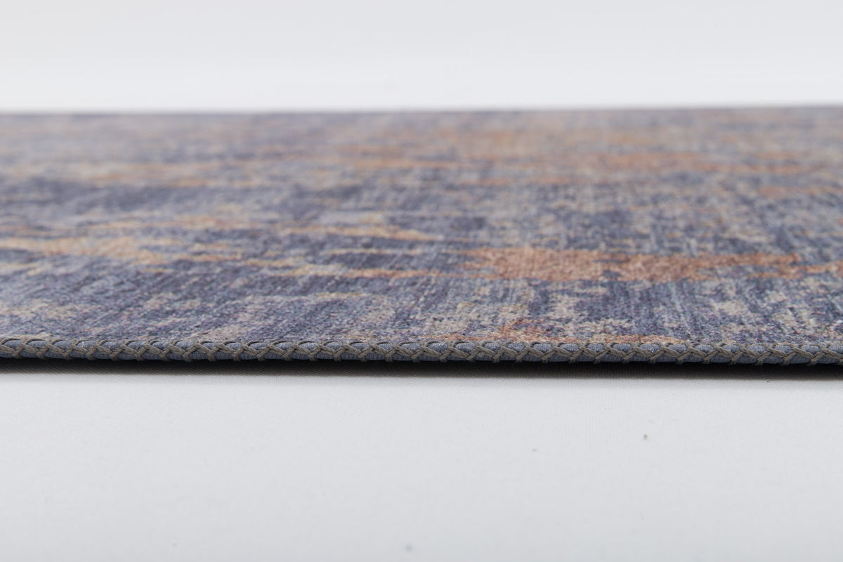 A close-up side view of the Mystical Mosaic - Washable Rug - JRS003 (Outlet) US shows its thin, flat design with a textured blue and brown pattern and braided edge—perfect for high-traffic areas.